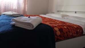 A hotel room with a bed, a blue and red patterned bedspread, and a white towel on the bed. - B&B Colombo (Pisa)