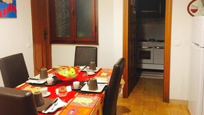 A dining area with a table set for four, a kitchen visible through an open door, and a refrigerator to the right. - B&B Colombo (Pisa)