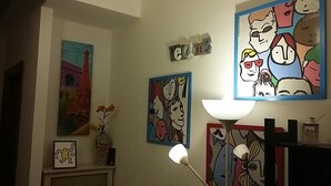 A room with a painting of the Eiffel Tower, a lamp, and a framed picture on the wall. - B&B Colombo (Pisa)