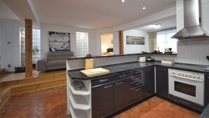 A modern kitchen with dark cabinetry, a central island, and a built-in oven.