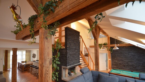 A spacious living area with a pool table, a fireplace, and a dining area with a wooden ceiling.