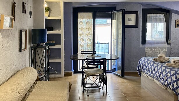 Ein Zimmer mit einem Bett, einem kleinen Tisch mit Stühlen, einem Fernseher und einem Fenster mit Vorhängen.
