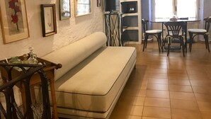 Ein Wohnzimmer mit einer Couch, einem Esstisch mit Stühlen, einem Kamin und verschiedenen gerahmten Bildern an den Wänden.