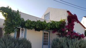 A building with a white exterior, a blue door, and a window. There is a cobblestone pathway leading to the entrance. - Casa Azul: Tranquility and tranquility in the ocean (Foz do Arelho)