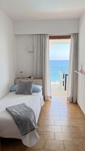 A bedroom with a bed, a nightstand, a window with curtains, and a view of the sea. - Exclusive Seafront Villa with Pool & Panoramic Views (Santa Ponça)