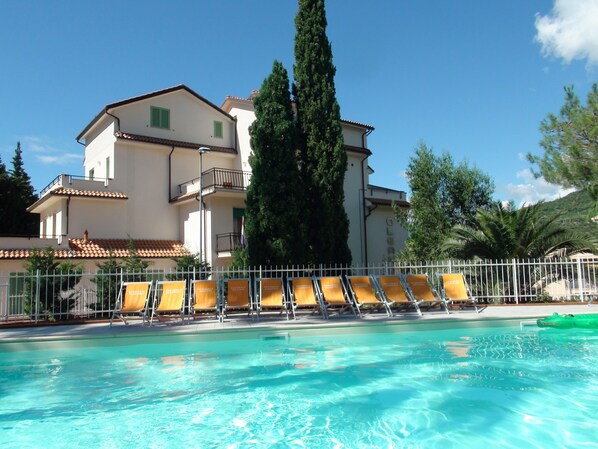 A pool area with sun loungers and a building with balconies in the background. - Family & Bike Friendly - Pool - Parking - Beach - WiFi - Air Conditioning - Bar (Pietra Ligure)
