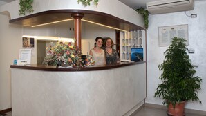 A reception area with a curved counter, a floral arrangement, and a potted plant.
