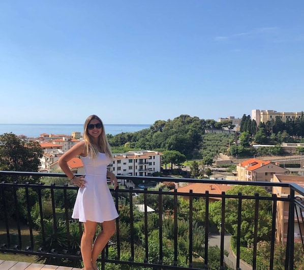 A balcony with a view of a coastal town and the sea.
