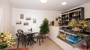 A restaurant with a bar area, a table with chairs, and a display case with beverages.