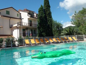 A swimming pool with lounge chairs and a green inflatable crocodile float. - Family & Bike Friendly - Pool - Parking - Beach - WiFi - Air Conditioning - Bar (Pietra Ligure)