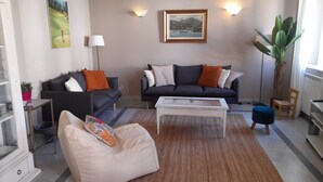 A living room with two sofas, a coffee table, a bean bag, a floor lamp, and a large plant. - Apartment near the sea with garage (Viareggio)
