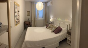 A bedroom with a bed, bedside table, lamp, and a hanging light fixture. - Apartment near the sea with garage (Viareggio)
