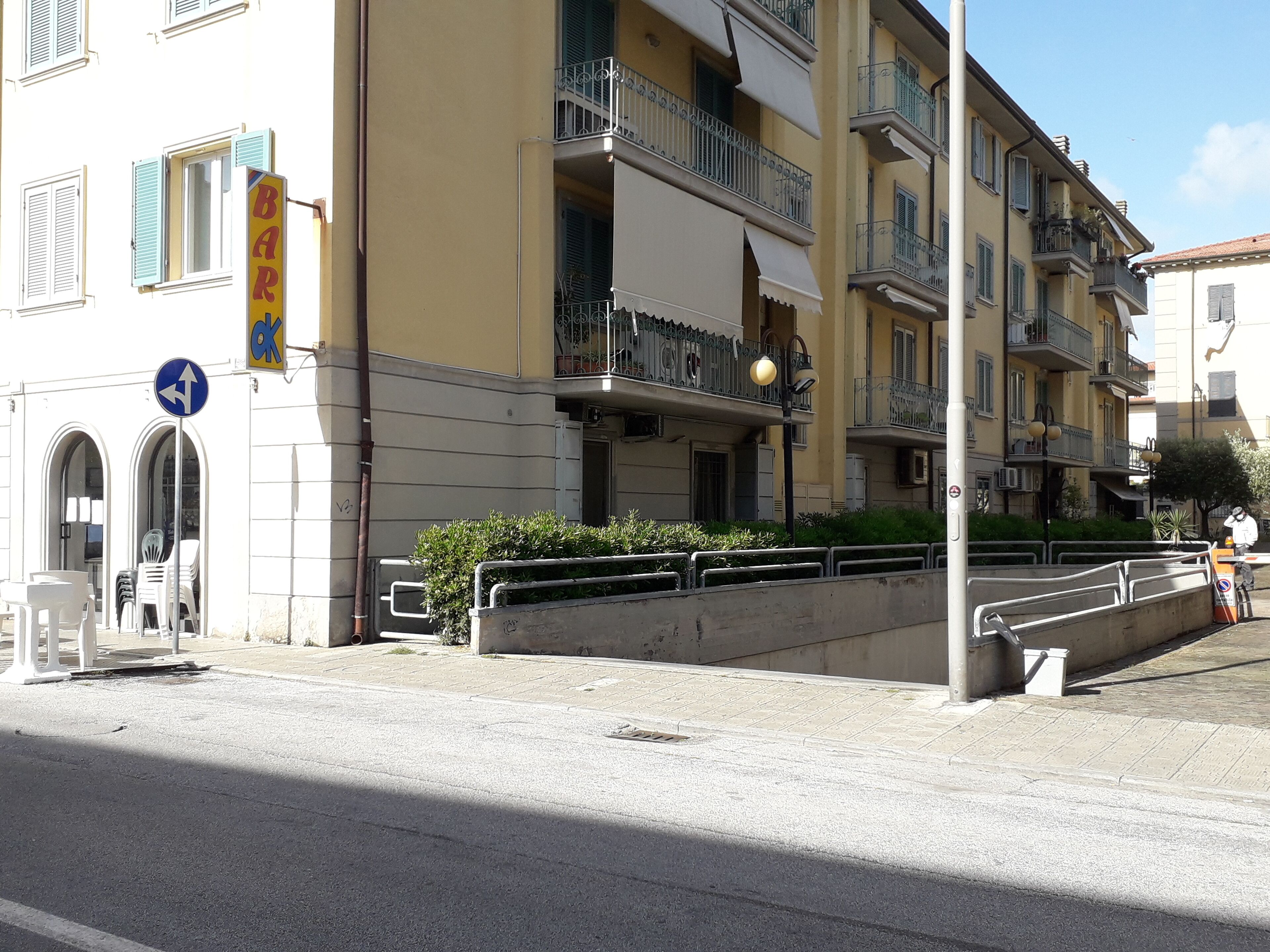 Un immeuble à plusieurs étages doté de balcons, un panneau de signalisation et un trottoir.