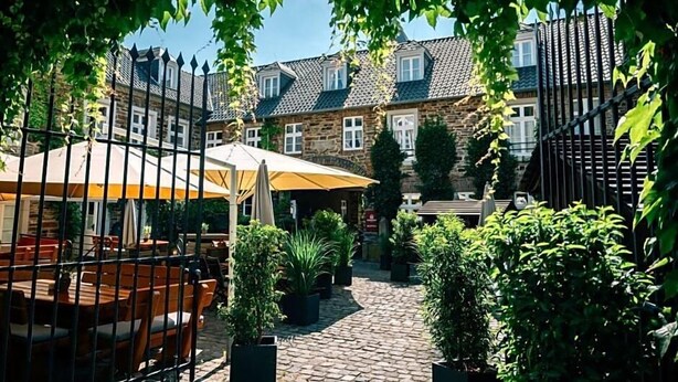 A courtyard with stone buildings, outdoor seating, and potted plants. - Rodderhof (Bad Neuenahr-Ahrweiler)