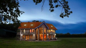 Ein zweistöckiges Haus mit rotem Dach, großen Fenstern und einer Veranda.