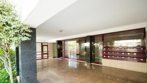 Un vestíbulo moderno con suelo de mármol, puerta de cristal y una planta en maceta.
