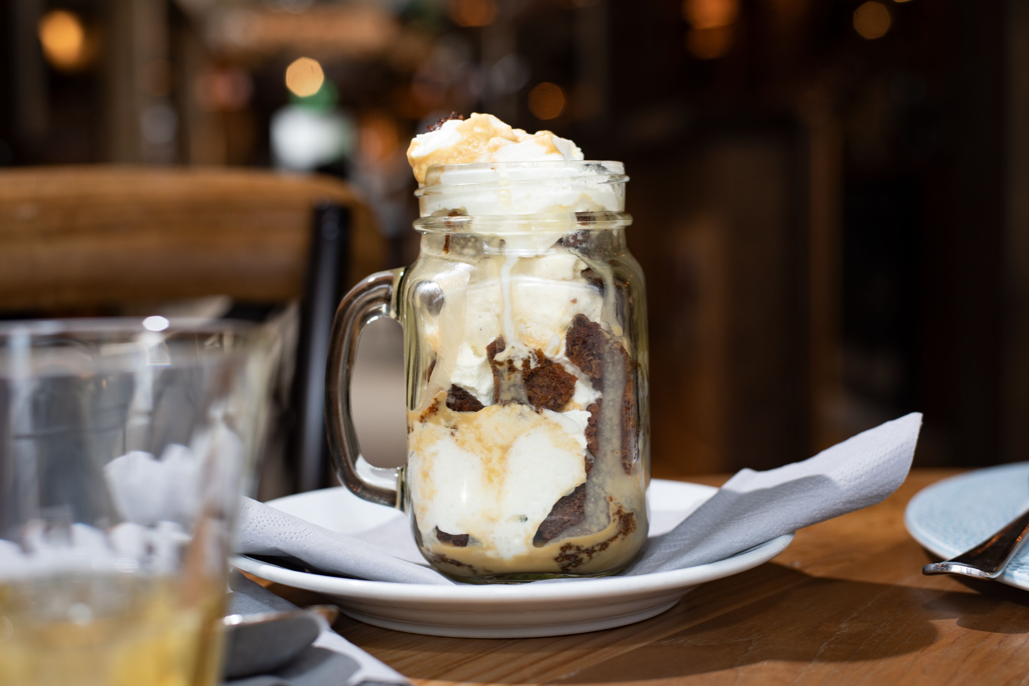 A dessert in a glass jar on a plate.