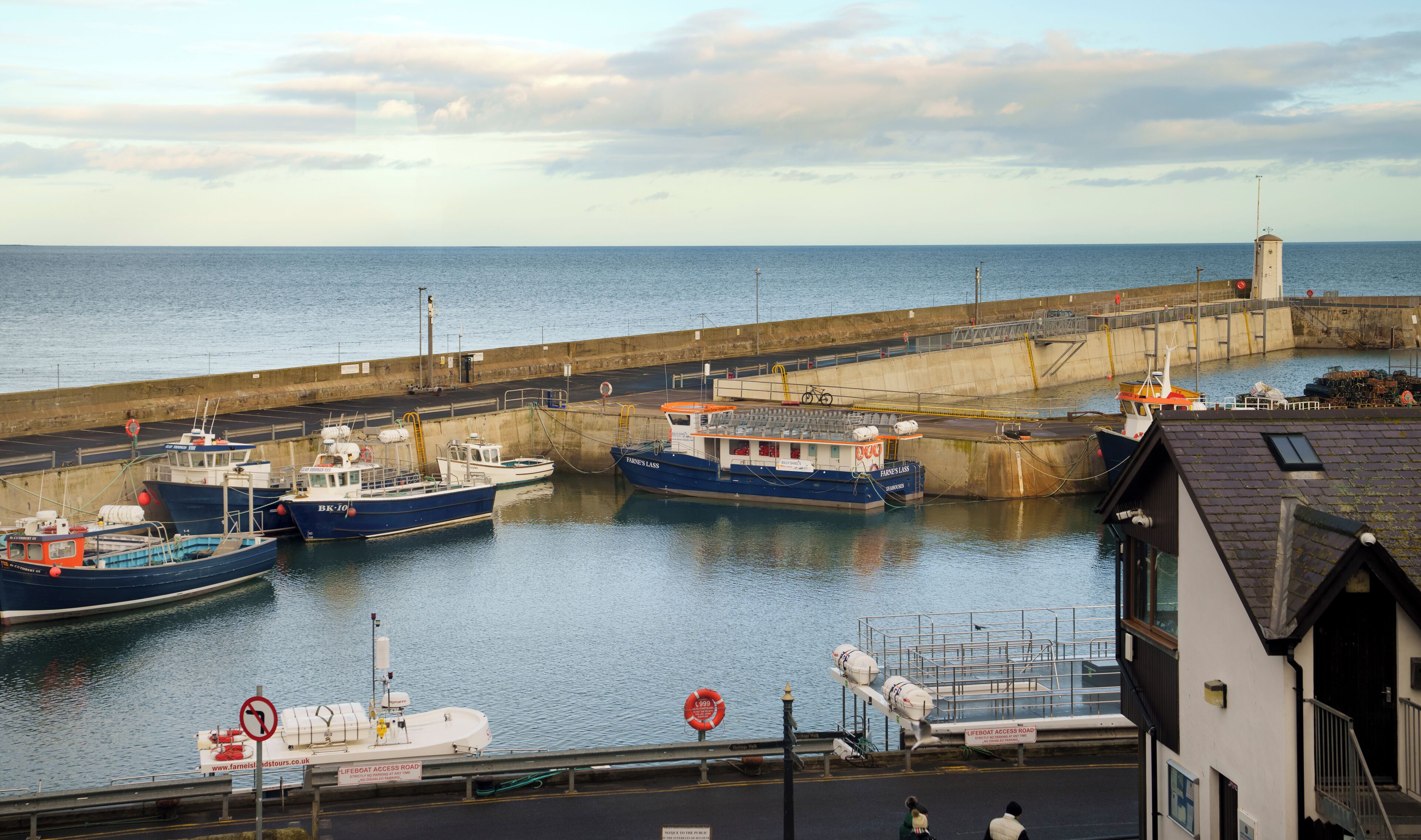 A harbor with several boats docked at a pier, a lifeboat access road, and a lifeboat on the dock.