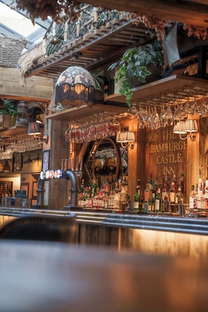 A bar area with a wooden interior, shelves with bottles, and a sign for 'The Bamburgh Castle Inn'. - The Bamburgh Castle Inn - The Inn Collection Group (Seahouses)