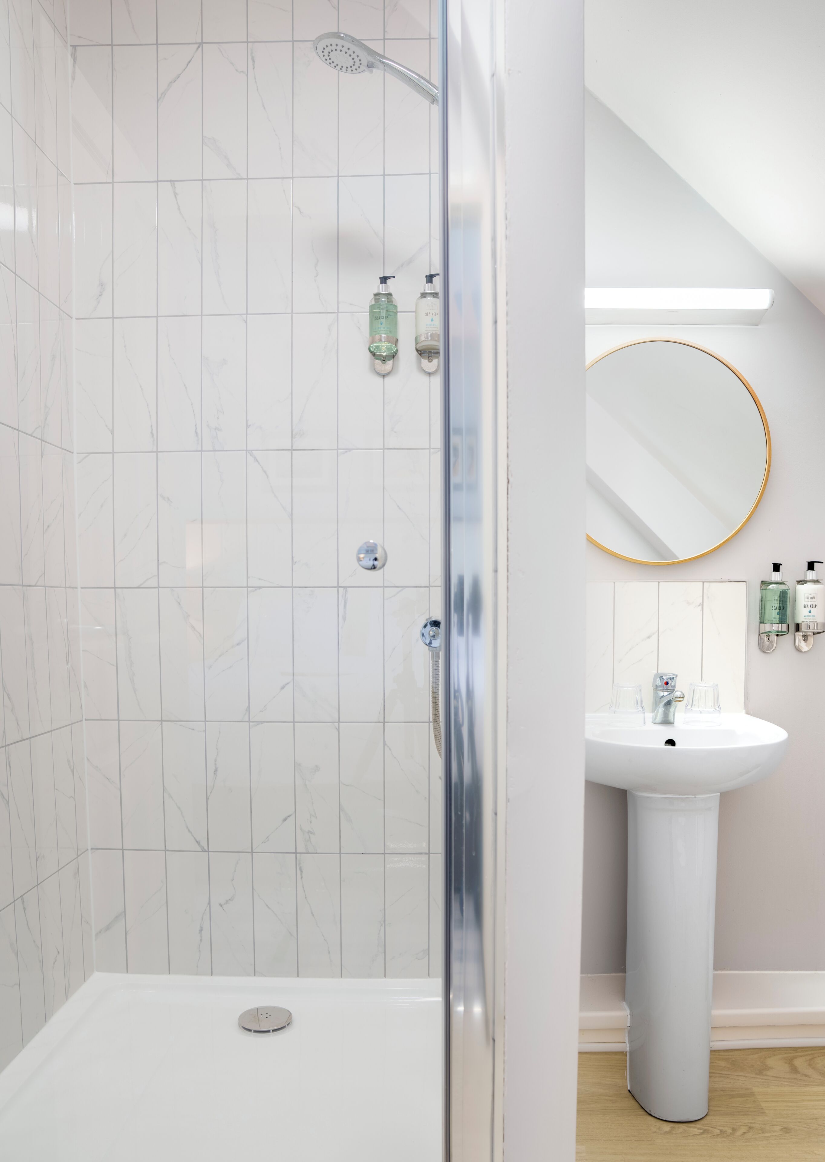 A modern bathroom with a shower, a sink, and a mirror.