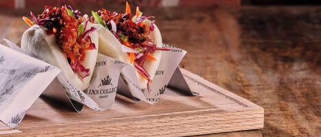 Two food items on a wooden board with a brick wall in the background.