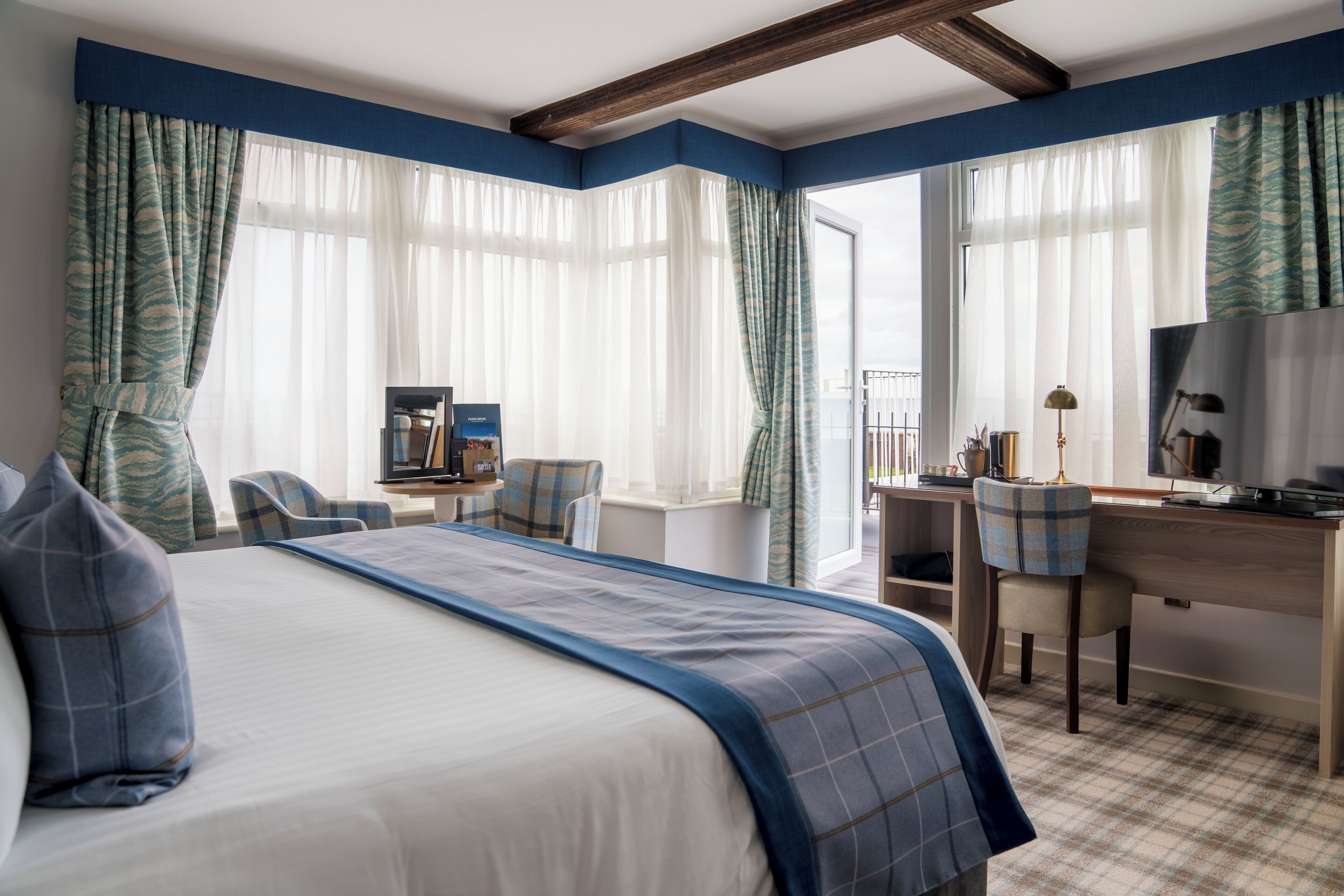 A hotel room with a large bed, a desk, a chair, and a television.