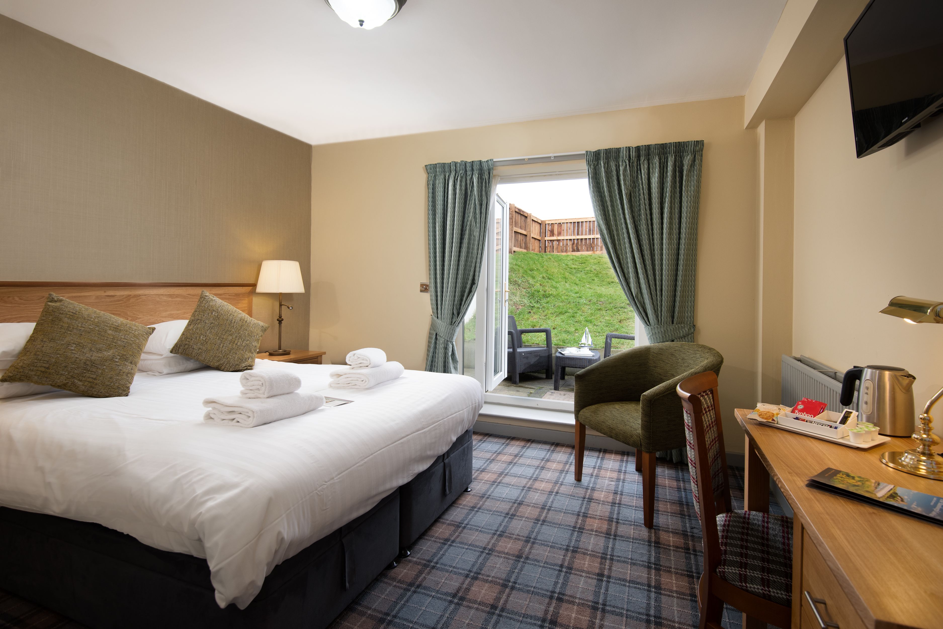 Ein Hotelzimmer mit Bett, Schreibtisch, Stuhl, Fernseher und Blick auf einen Hinterhof.