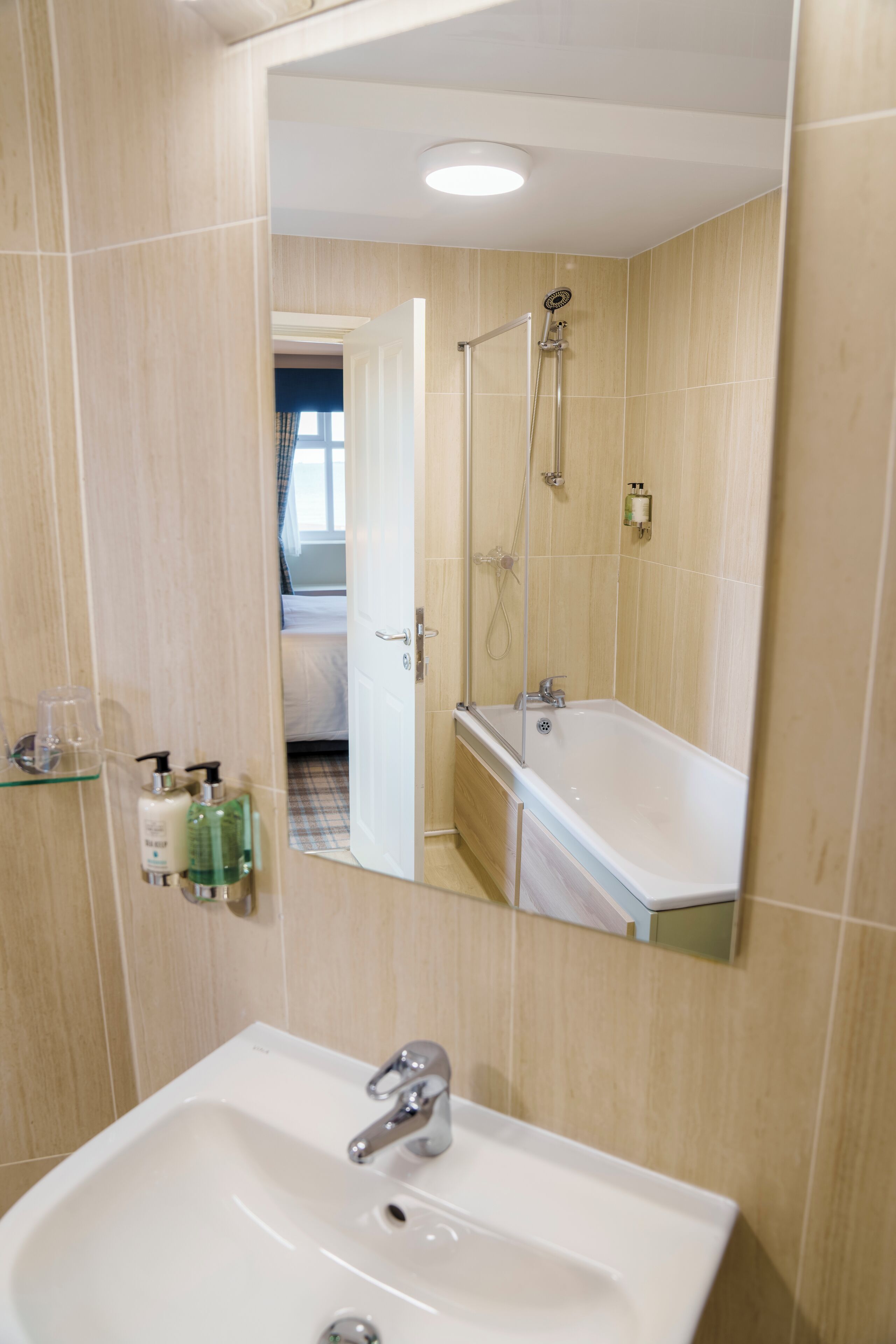 A bathroom with a sink, mirror, and shower.