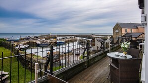 Een balkon met uitzicht op een haven, inclusief boten en een gebouw.