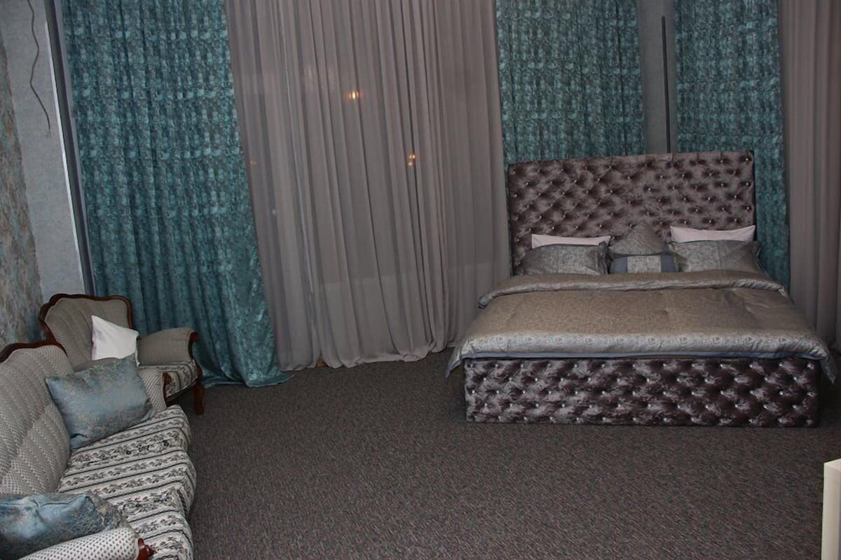 Un dormitorio con una cama grande, un sofá y cortinas.