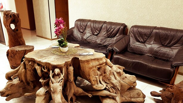 A round wooden coffee table with a natural wood finish and a vase with flowers. - Hotel Makona (Tbilisi)