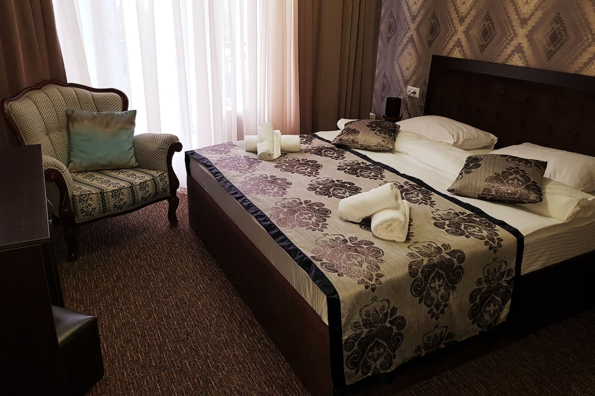 Una habitación de hotel con una cama grande, una silla y un escritorio.