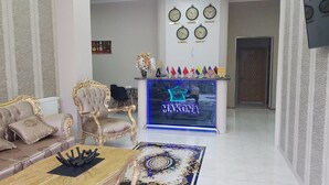 A spacious living area with a sofa, armchair, and coffee table. A neon sign with the word "MOKONA" is visible. - Hotel Makona (Tbilisi)