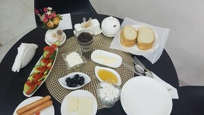 A table set for breakfast with various dishes, including bread, cheese, and vegetables. - Hotel Makona (Tbilisi)