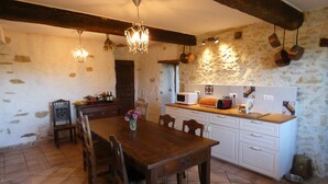 Une cuisine rustique avec une table et des chaises en bois, un mur en pierre et des appareils électroménagers simples.