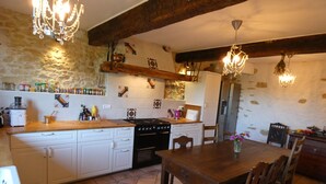 Une cuisine avec un îlot central en bois, des meubles blancs, une cuisinière et une table à manger avec des chaises.