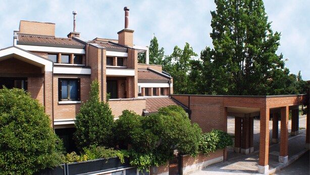 Un edifici modern de diversos pisos, façana de maó, finestres grans i zona exterior coberta.