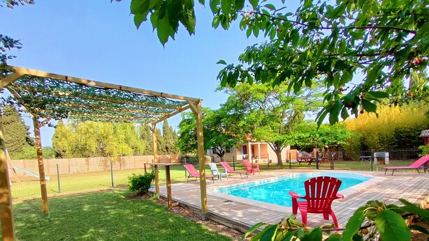 Un jardin avec une pergola en bois, une piscine et des fauteuils Adirondack rouges.