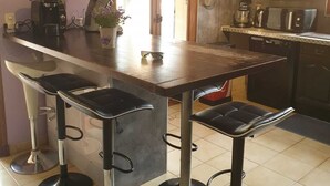 Une cuisine dotée d’un îlot central en bois, de tabourets de bar et d’appareils électroménagers modernes.