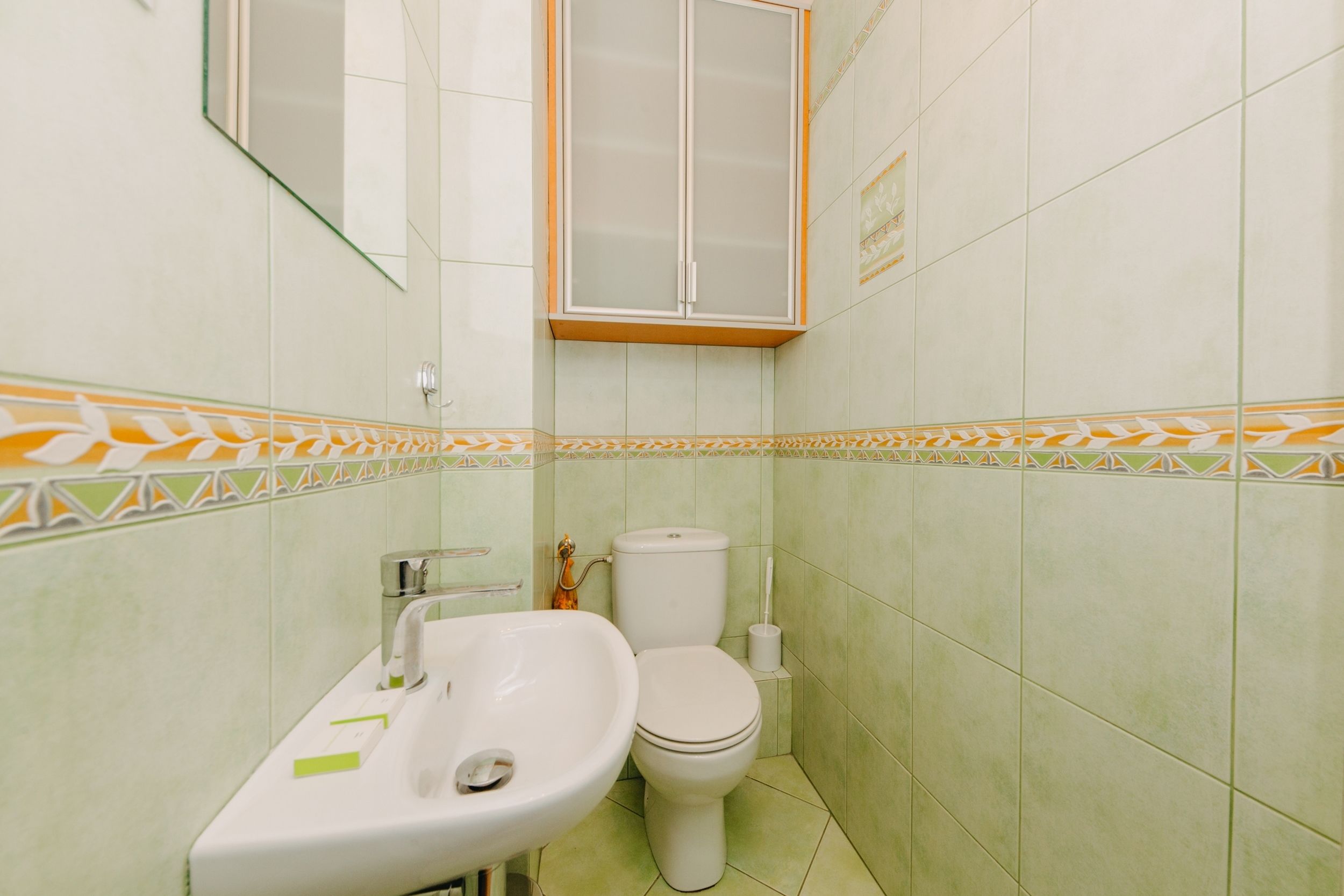 Une salle de bain avec un lavabo, des toilettes et un meuble de rangement.