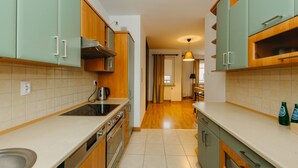 A kitchen with wooden cabinets, a stove, and a sink. - ShortStayPoland Krochmalna - B39 (Warsaw)