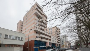 A multi-story residential building with balconies, a parking area with cars, and a snow-covered ground. - ShortStayPoland Krochmalna - B39 (Warsaw)
