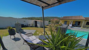 Une terrasse couverte avec une piscine, des chaises longues et des plantes en pot.