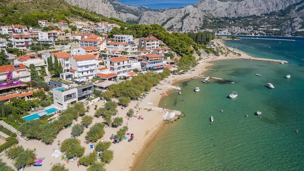 Une ville côtière avec des bâtiments qui bordent la plage et des bateaux sur l’eau.