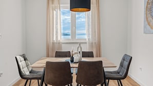 Un coin repas avec une table en bois, quatre chaises, un vase contenant des fleurs séchées et une suspension.