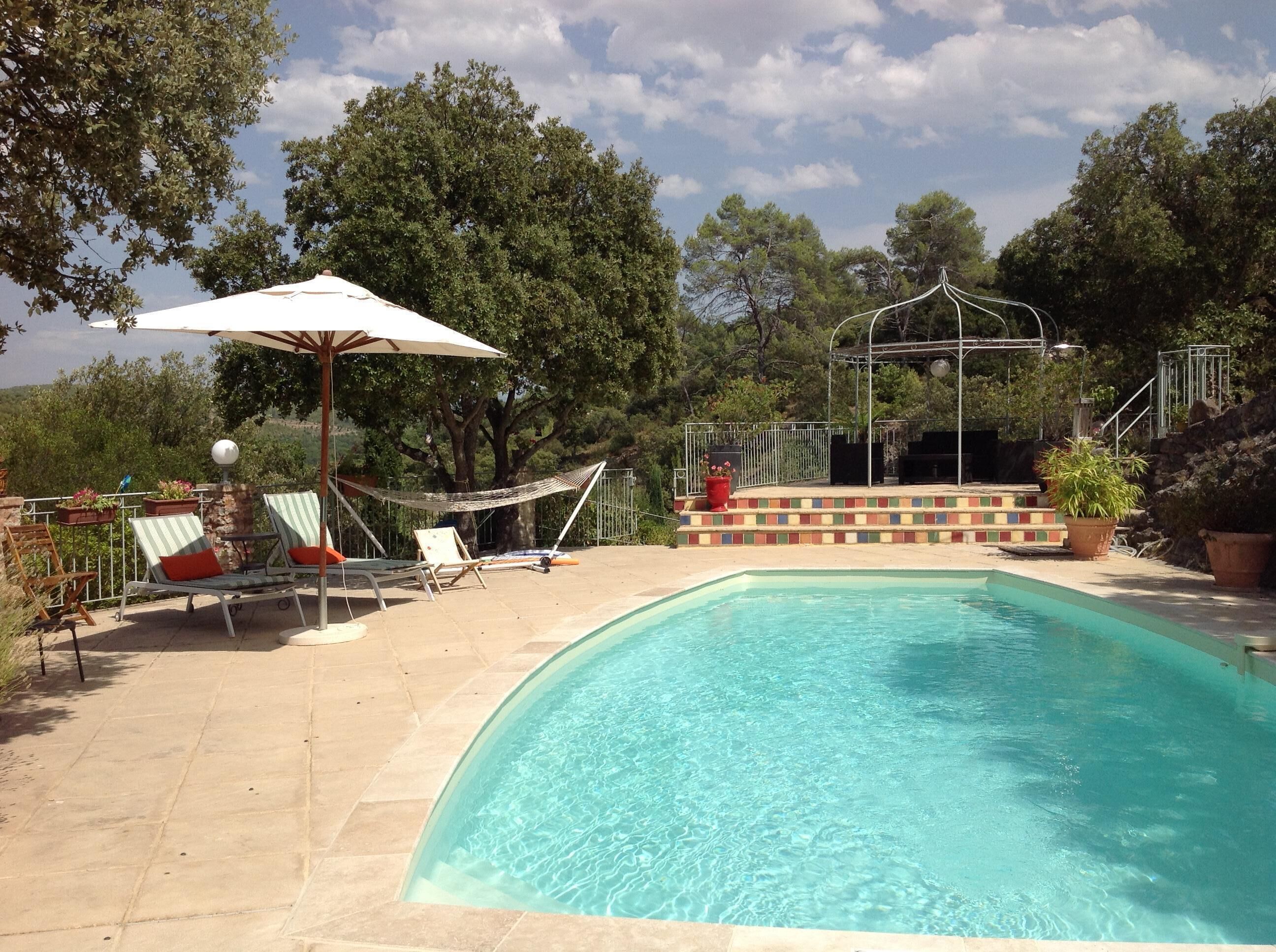 A swimming pool with lounge chairs and a hammock.