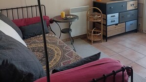 A room with a bed, a table with a candle, a TV, and a dresser.