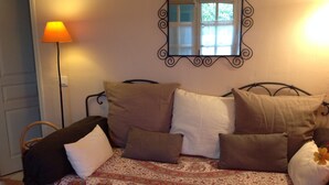A bed with a patterned bedspread, multiple pillows, a bedside lamp, and a mirror on the wall.