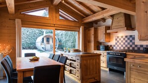 A wooden interior with a dining area, kitchen, and large windows.