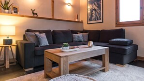 A modern living room with a dark-colored sectional sofa, a wooden coffee table, and a small side table with a lamp.
